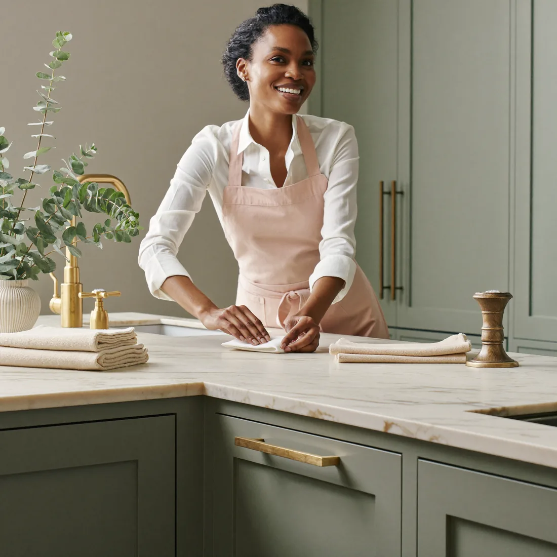 A Pink Planett housekeeper polishing a marble worktop in a bright London kitchen